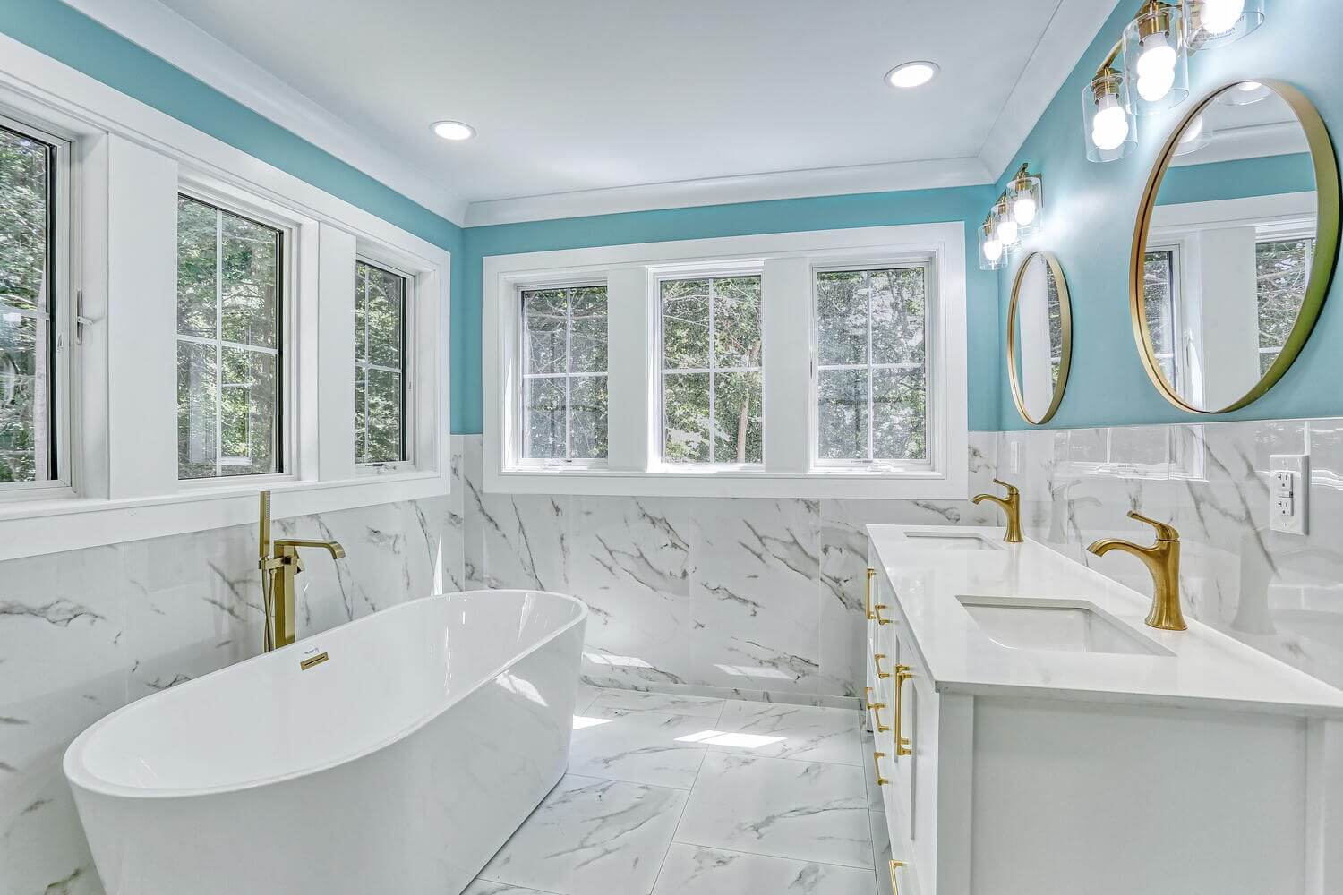 Primary bathroom with freestanding tub and marble walls by Dadak LLC